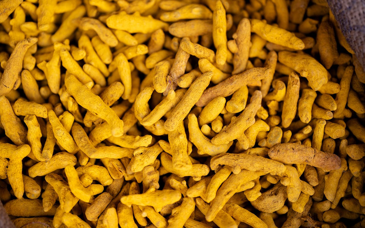 Detailed view of turmeric roots in a market setting, showcasing their vivid yellow color.