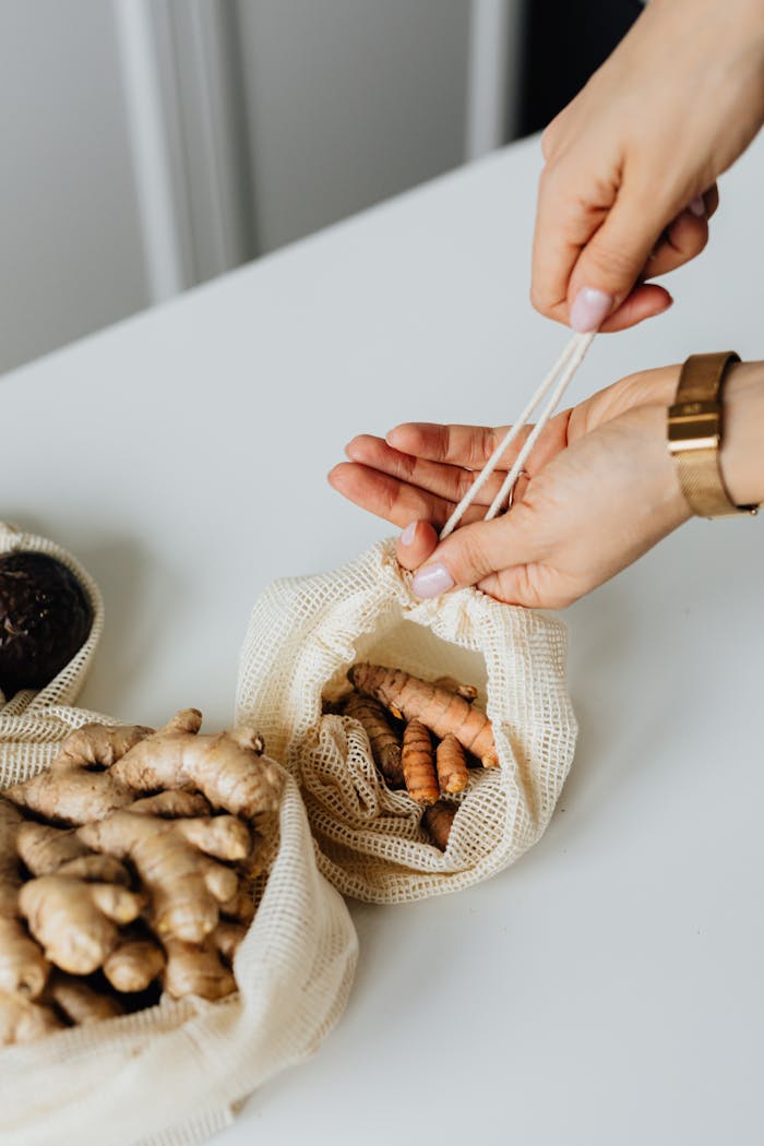 Close-up of hands packing ginger and turmeric into eco-friendly drawstring bags.